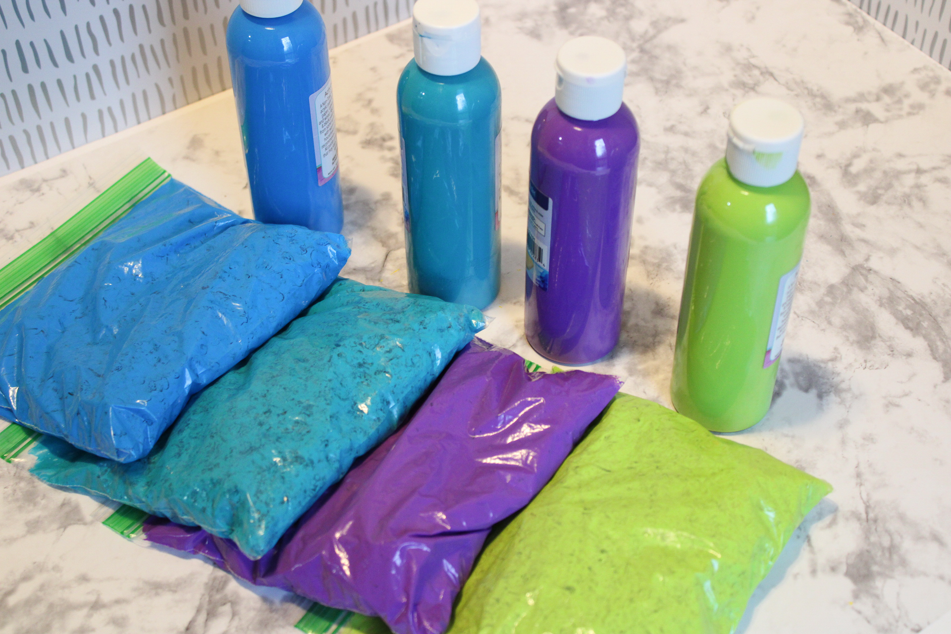 4 bags of chickpeas coated in paint next to the bottles of paint