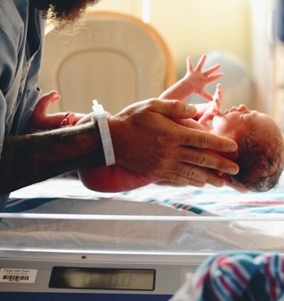 image of a man's hands placing a newborn into a hospital bed