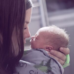 woman holding a newborn close and touching noses