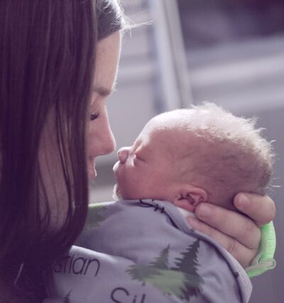 woman holding a newborn close and touching noses