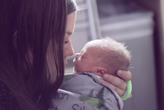 woman holding a newborn close and touching noses